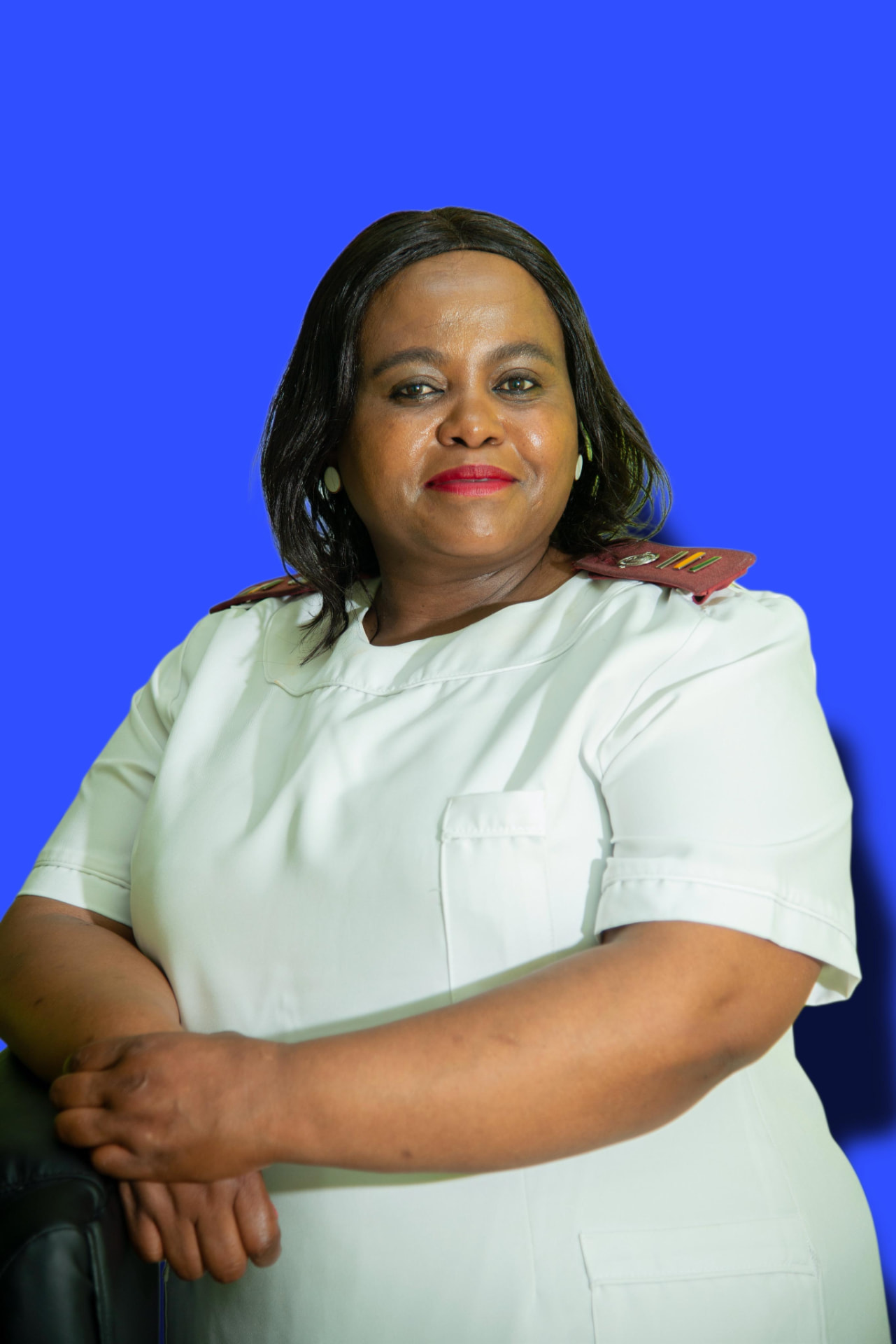 Funeka Sethaiso, the professional nurse at Dr T Matseke Practice, in a white nurse uniform against a blue background
